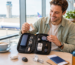 A man happily opens the pouch with tech travel accessories and gadgets at the airport lounge